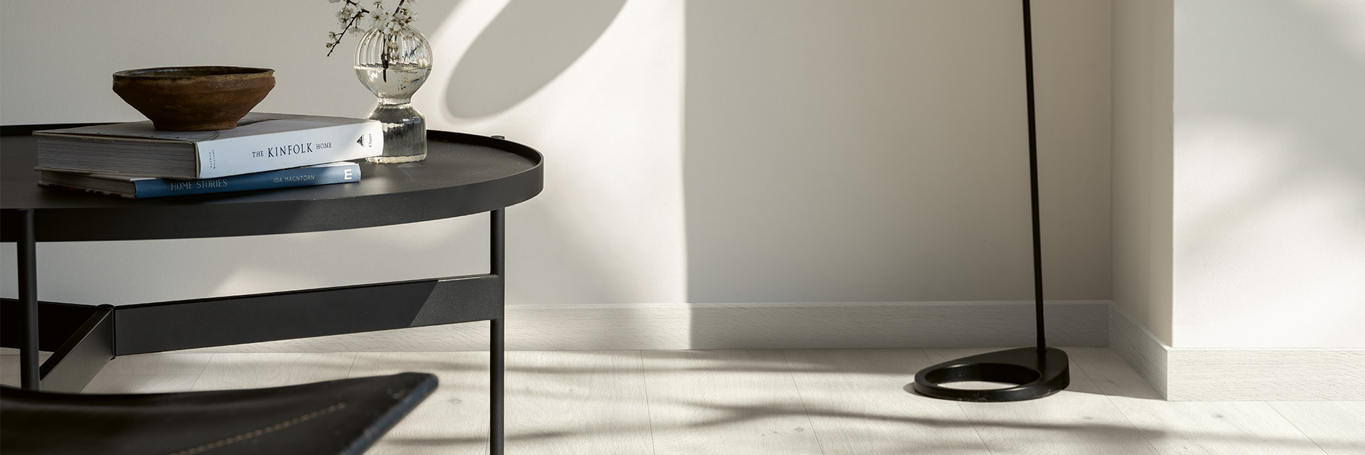 närbild av ett grått laminatgolv med matchande grå golvlister och ett soffbord